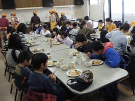 広い室内で食事をとる人々の写真