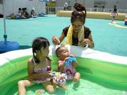 子ども用プールで遊ぶ親子の写真