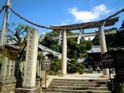 青空の下、矢田坐久志玉比古(やたにいますくしたまひこ)神社の鳥居を正面から写した写真