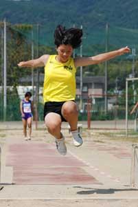 黄色いユニフォームを着た女の子が走り幅跳びをしている写真