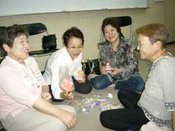床に座りキュウピイさんを手に持ち笑顔の女性4人の写真