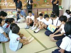 小学5年生の女子生徒が園児たちに絵本の読み聞かせをしている写真