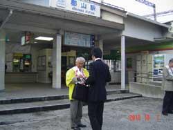 郡山駅前に立つ黄色い上着を着た男性が持つ募金箱に募金のため立ち止まるサラリーマンの写真