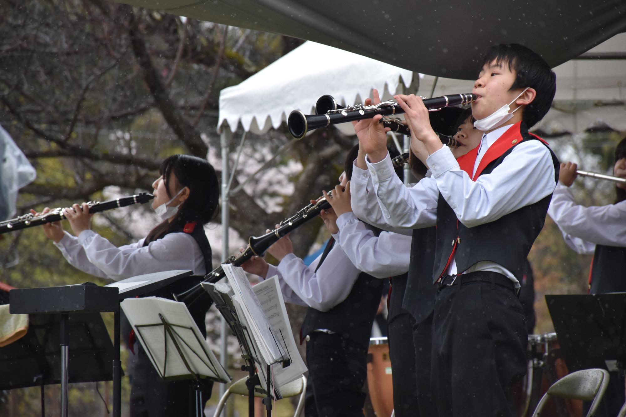 赤い襟のついたベストを着て演奏する中学生たち