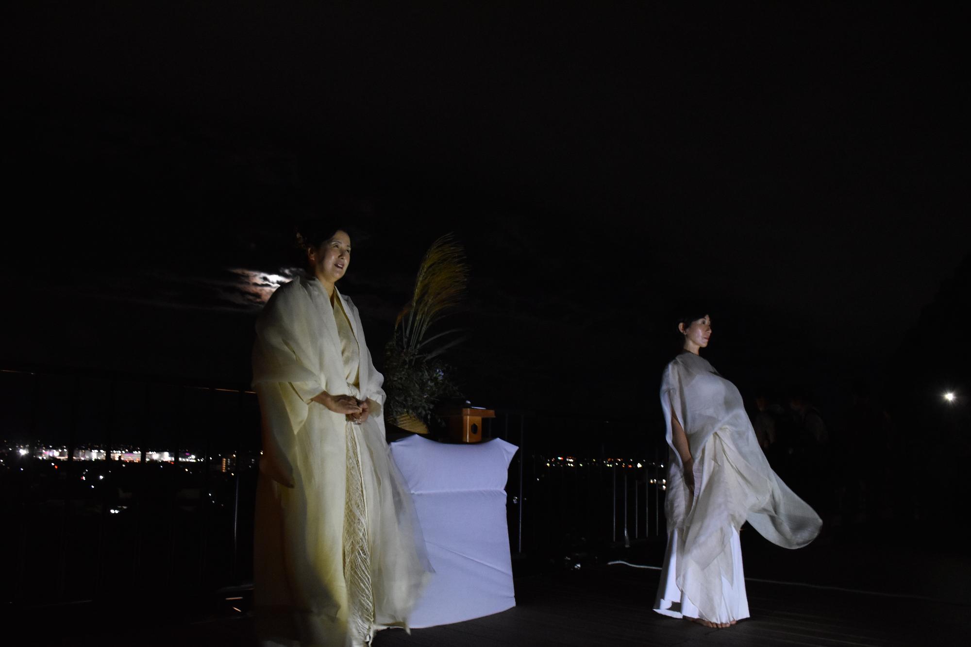 展望施設で古事記の朗誦を行う白い衣装を着た女性と、舞踊を披露する白い衣装を着た女性