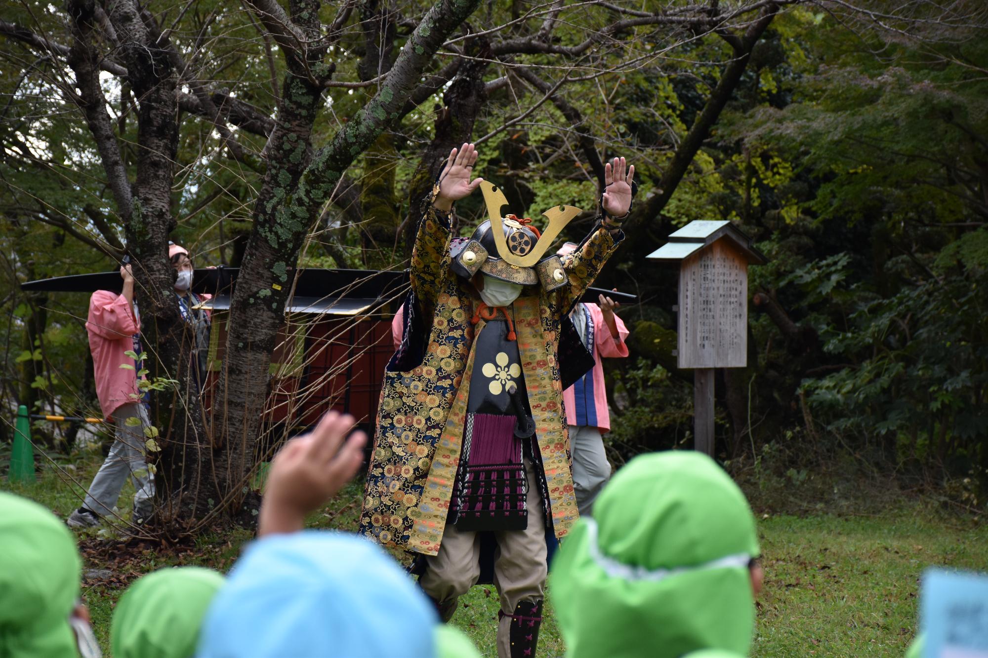 鎧兜を付けたお殿様と籠を担いで登場したピンクの法被姿のちょんまげの家来4人