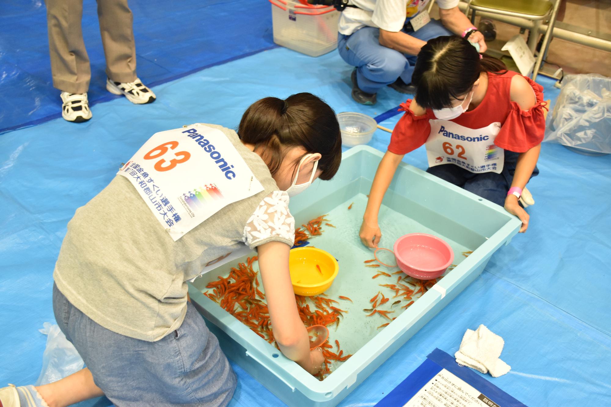 身を乗り出して金魚をすくう女の子たち