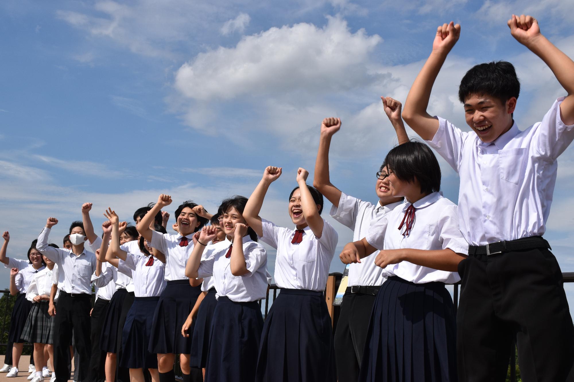 両手を挙げて撮影中の中学生達