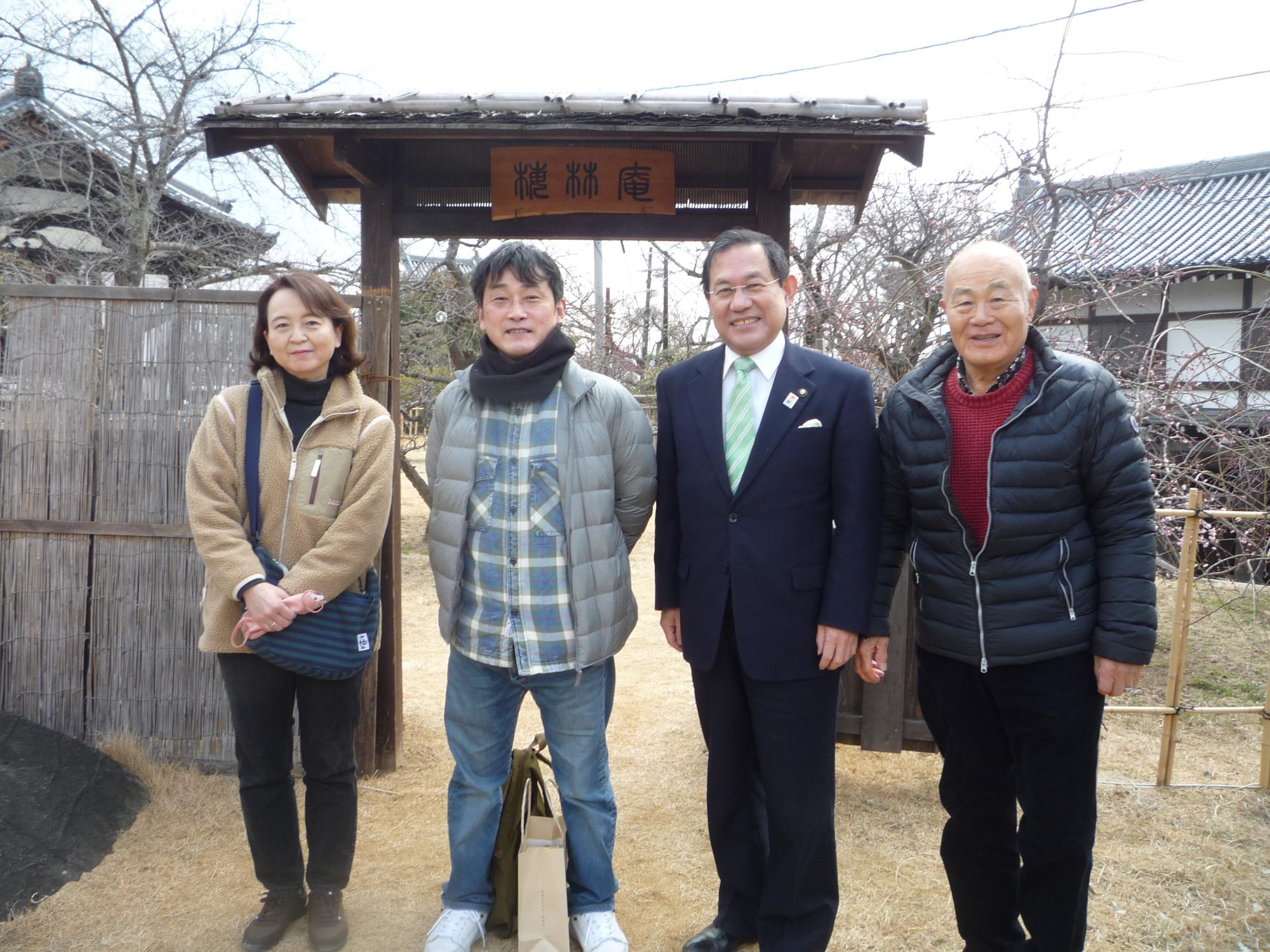 市長、大和郡山盆梅展実行委員会会長と盆梅展会場の入り口に並ぶ盆梅展5000人目の入場者となったご夫婦