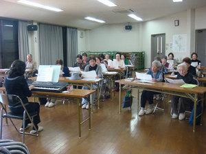 先生のキーボードに合わせて歌う泉寿会の人々の写真