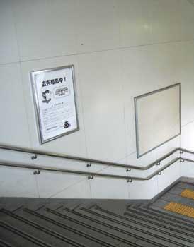 JR大和小泉駅前駅のポスター掲示場所：ポスターがはられている通路階段の壁の写真