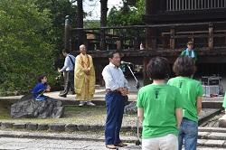 緑色のTシャツを着た2人の女性と白色のワイシャツを着た男性と僧侶が立っている写真
