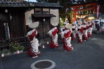建物の前で赤色と白色の和服を着て踊る人々の写真