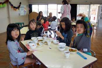 白いテーブルについて食事をしている4人の子供たちの写真
