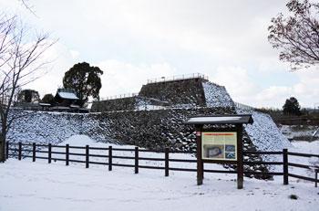青空の下郡山城跡の敷地内にある一部が雪に覆われている城の土台の写真