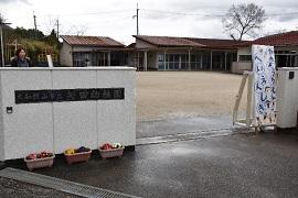「やたようちえんへいえんしき」と書かれた白い看板のある少し離れたところに赤い屋根の建物が見える矢田幼稚園の白い門の写真