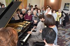 来場者に囲まれてピアノを弾く池宮さんの写真