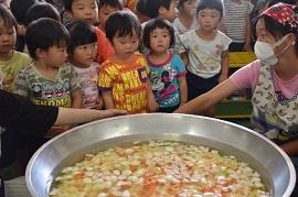 水と野菜が入った大きな鍋を興味深そうに見る子どもたちの写真1