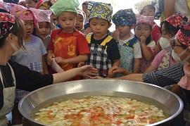水と野菜が入った大きな鍋を興味深そうに見る子どもたちの写真2
