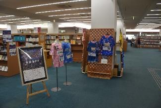 図書館の一角に奈良クラブの青と桃のユニフォームなどが展示されている様子の写真