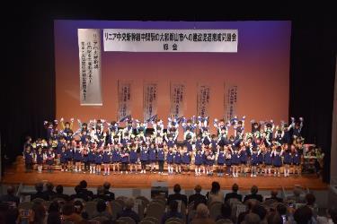 舞台上で大勢の幼稚園児たちが並び歌を歌っている写真