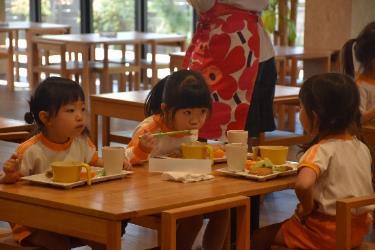 お雑煮を食べているオレンジ色のパンツを履いた3人の女の子の写真