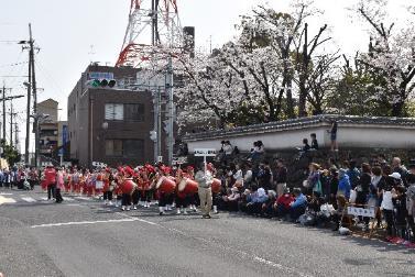 パレードで赤い衣装を着た参加者が太鼓を叩いている写真