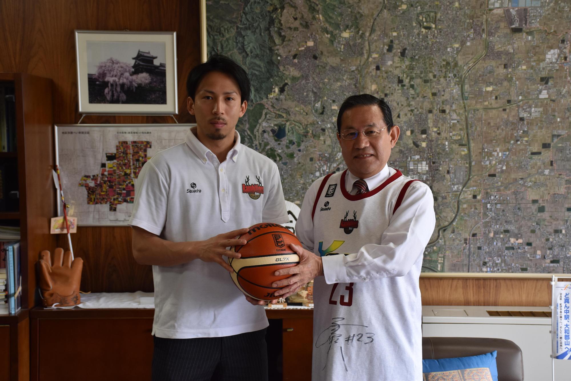 市長室で「バンビシャス奈良」の選手とユニフォームを着てボールを一緒に持って記念撮影をしている様子