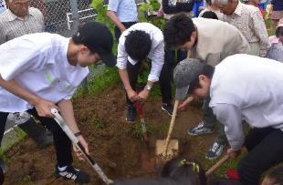郡山西小学校でシャベルで土を掘り起こす元生徒たちの写真