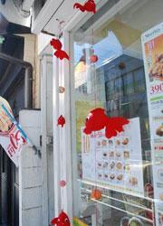 飲食店のショウウィンドウの前に飾られた赤い金魚の工芸品の写真