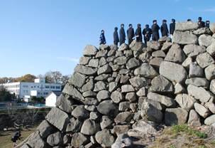 郡山城の石垣に立つ生徒たちの写真