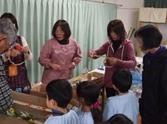 講師のフラワーデザイナー田中友子さんとしめ縄をつくる園児と母親たちの写真