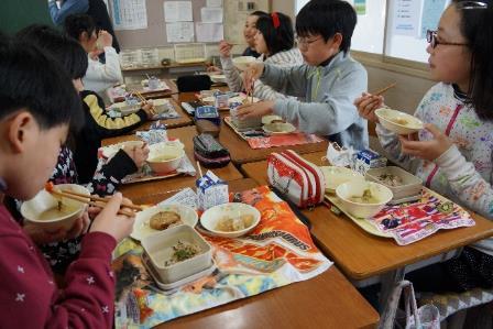 教室内で食事をしている小学生男女の写真