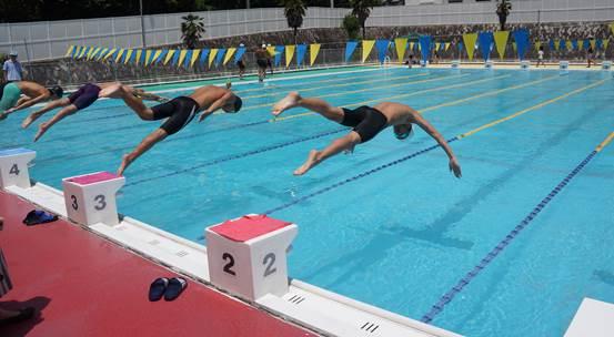 プールの飛び込み台から水の中に飛び込む水着姿の4人の男性の写真
