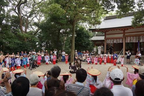 賣太神社の境内で一本の木を囲むように集まる着物を着て三度傘を被った女性や祭りの来場者たちの写真