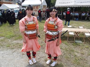桃色の着物とオレンジ色の甲冑を着た二人の女子高校生の写真