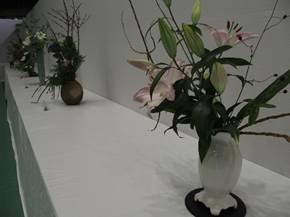白い布を被せた長机の上に花が咲いた植物の入った花瓶がいくつか並んでいる写真
