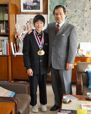 市長室で金メダルを2つ首からかけた男子中学生と、その肩に手をかけている市長の写真