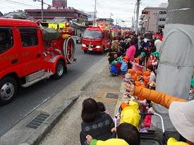 路地を走行する消防車と見物する保育園の子供たちの写真