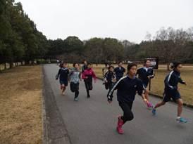 曇り空の公園を走って、練習する子供たちの正面アングルの写真