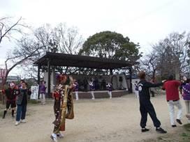 着物を着た女性や黒い繋ぎの男性が踊りを踊っている処の写真