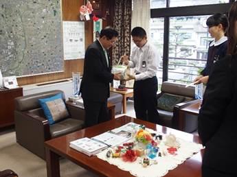 執務室で、市長に義援金を手渡す生徒たちの写真