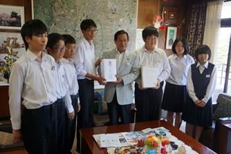 執務室で、市長に義援金を渡し一緒に記念撮影をする7人の中学生の写真