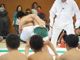 相撲の取り組みが始まり、組み合う二人のちびっ子力士の写真