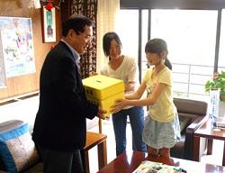 執務室で、市長に義援金を手渡す2人の女子児童たちの写真