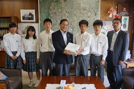 5人の中学生が執務室で、市長に義援金を手渡している処の写真