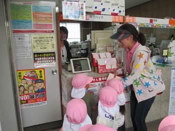 ピンクの帽子を被った園児たちが郵便局の窓口を訪れた時の写真
