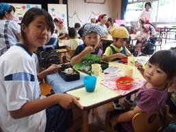 園児たちとカレーを食べる中学生の写真