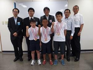 相撲全国大会に出場するメダルを付けた3人の子供と5人の関係者の写真