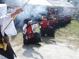 筒井城跡で行われた「筒井順慶まつり」でしゃがんで空に向かい火縄銃を構えている様子と「祝砲」を発射した写真